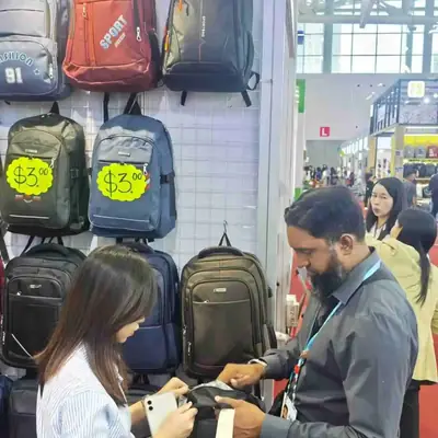 Buyer trying a laptop backpack beside the SANDA bag display wall